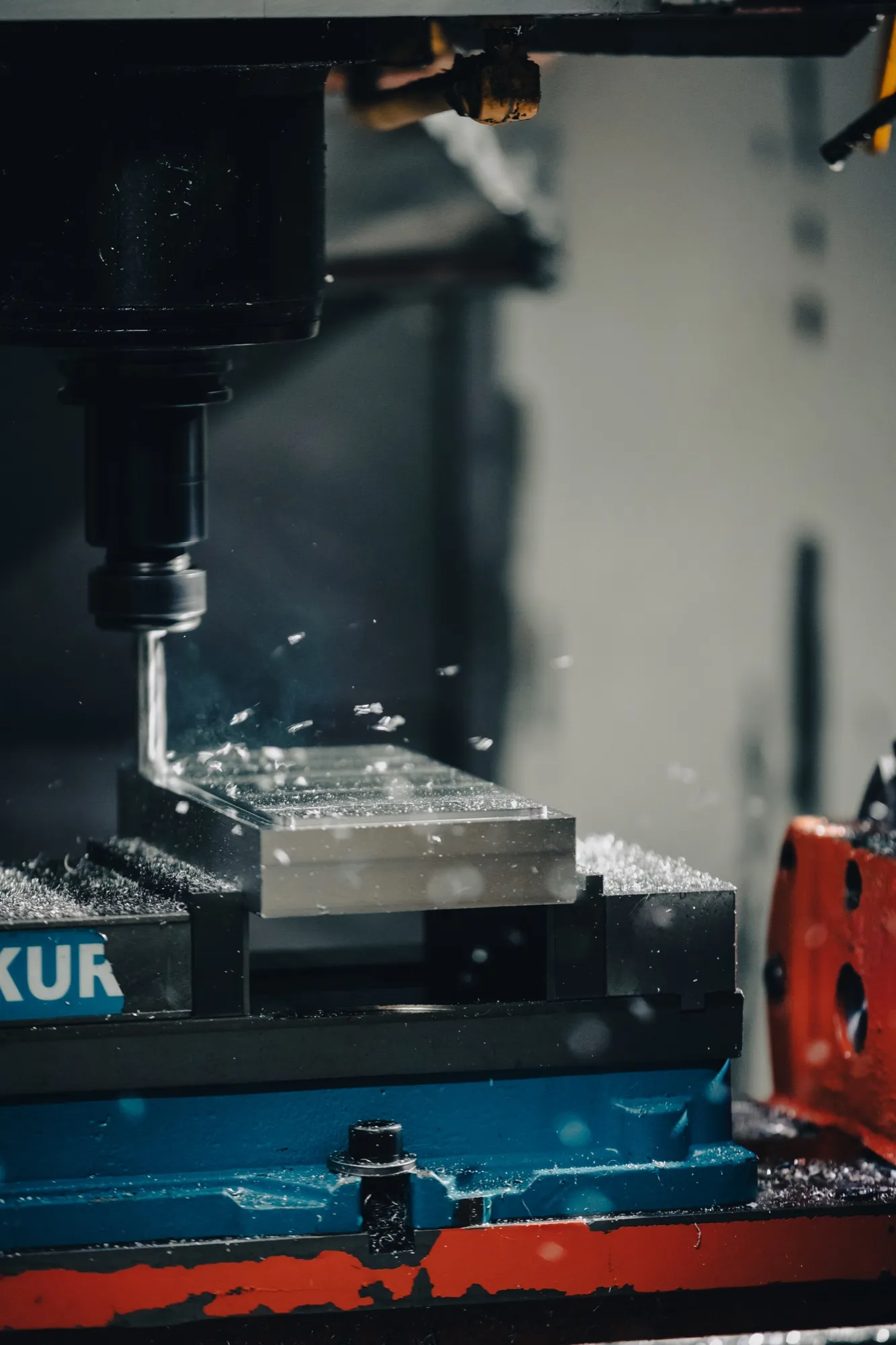 machining equipment carving into a metal block and metal shavings being thrown around it