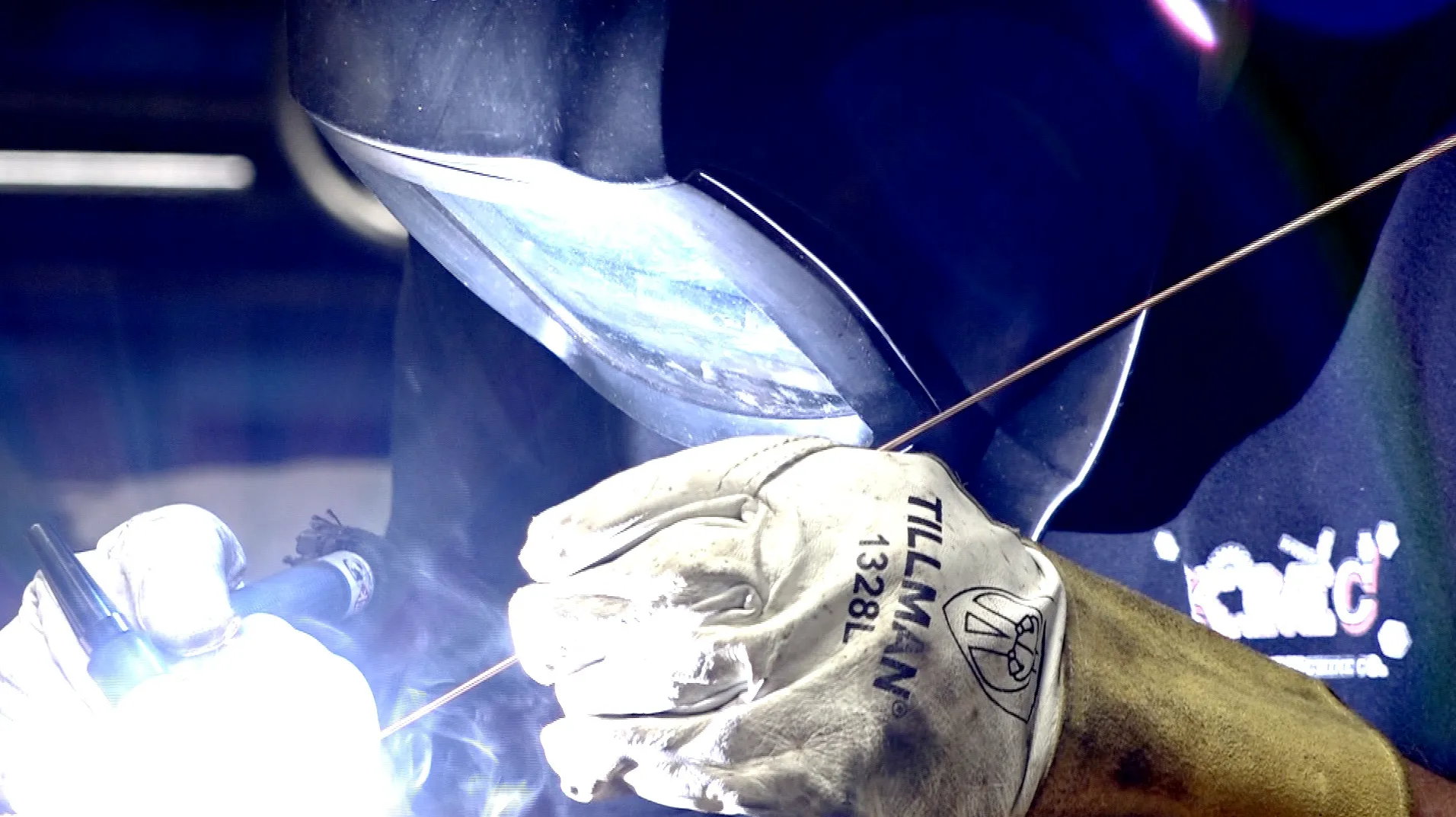masked worker welding with blue flame